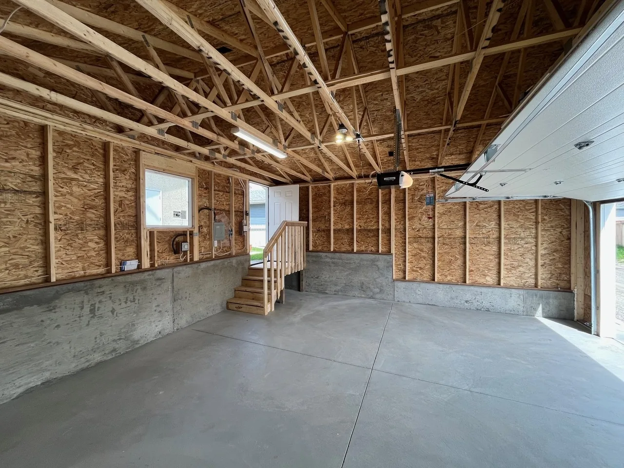 An open-framed interior with concrete stem walls and wood stairs to a door