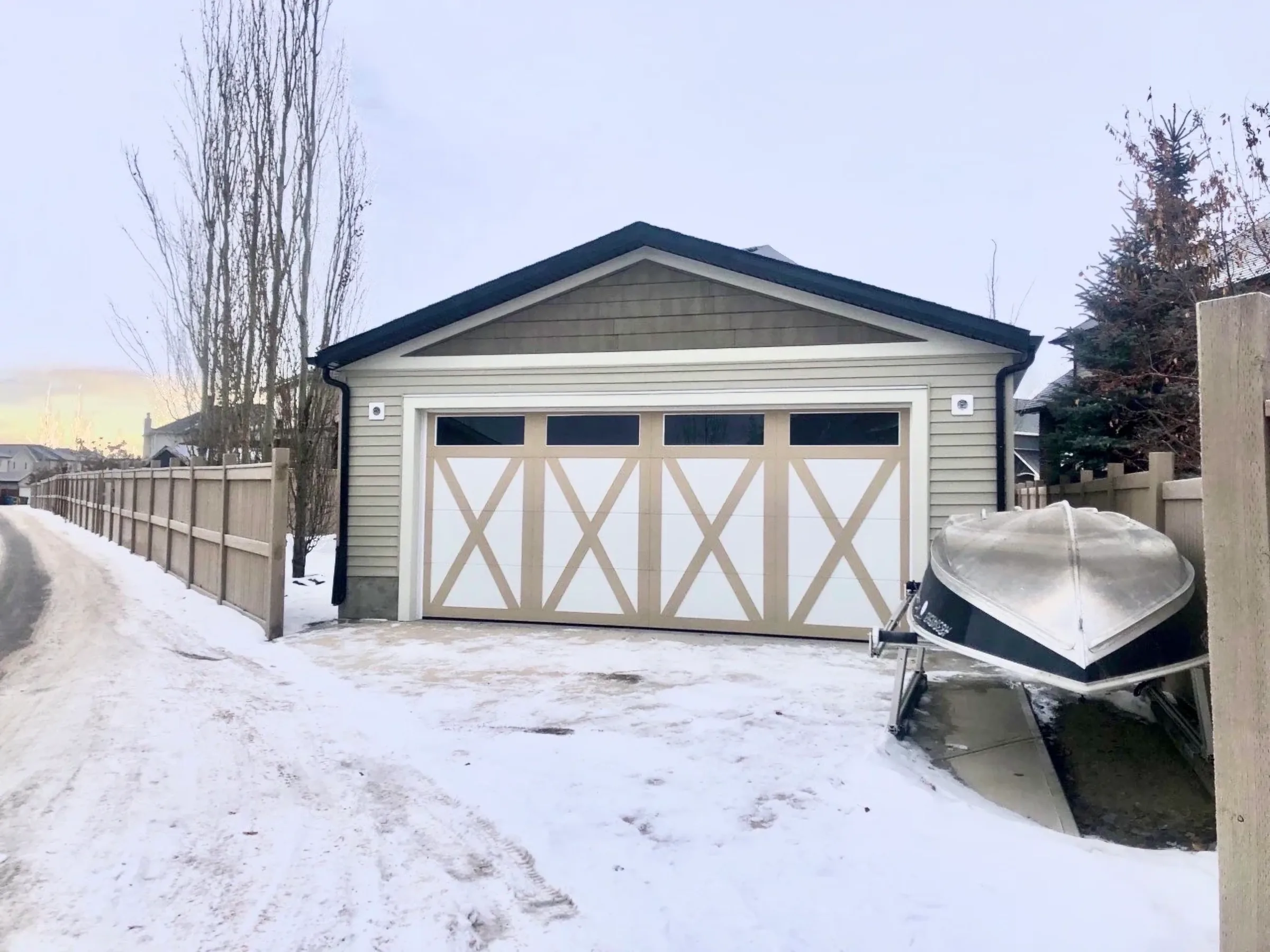A detached garage with carriage-style doors built by Alliance Renovations, in winter snow